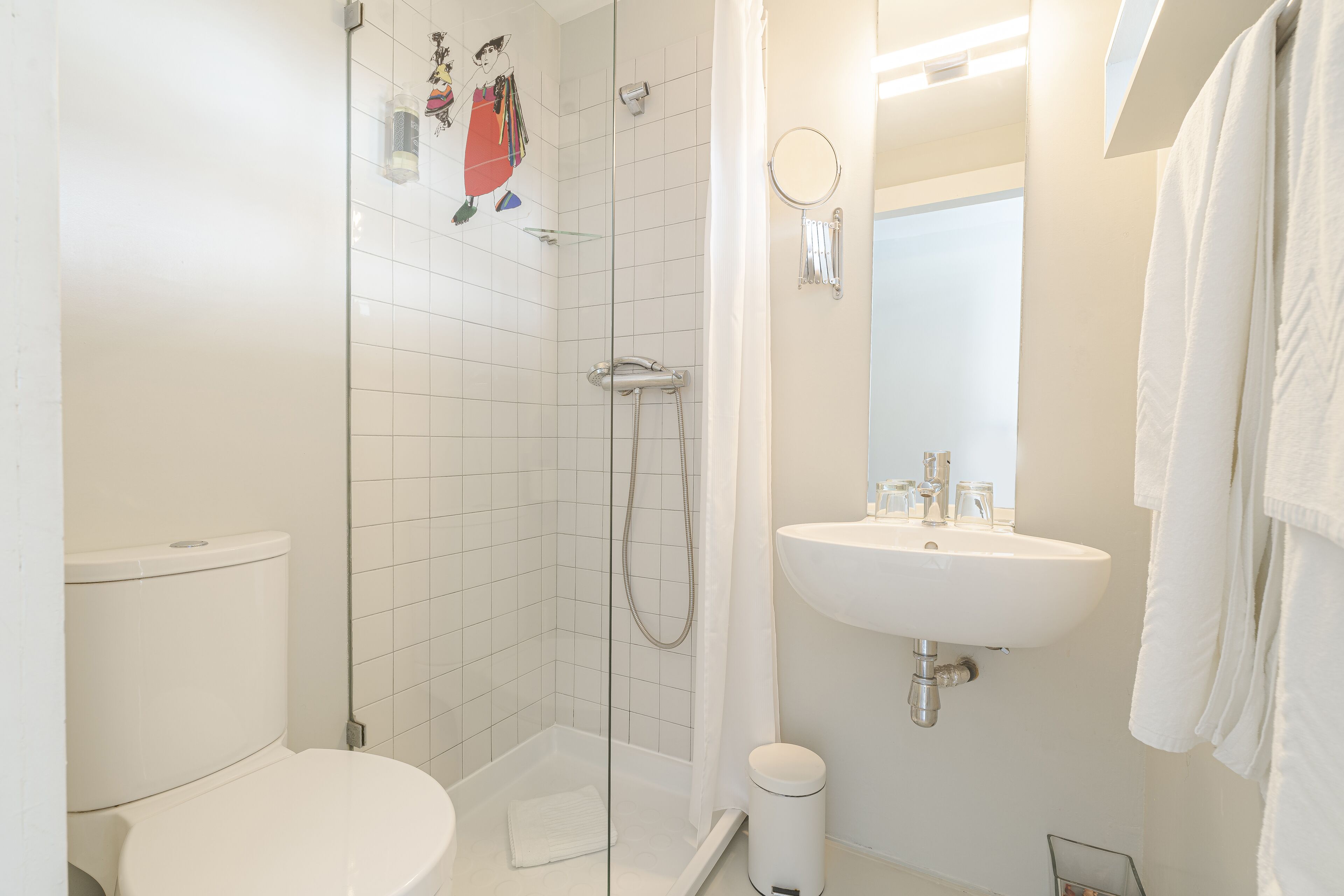 A bathroom with a toilet, a glass-enclosed shower, and a sink.