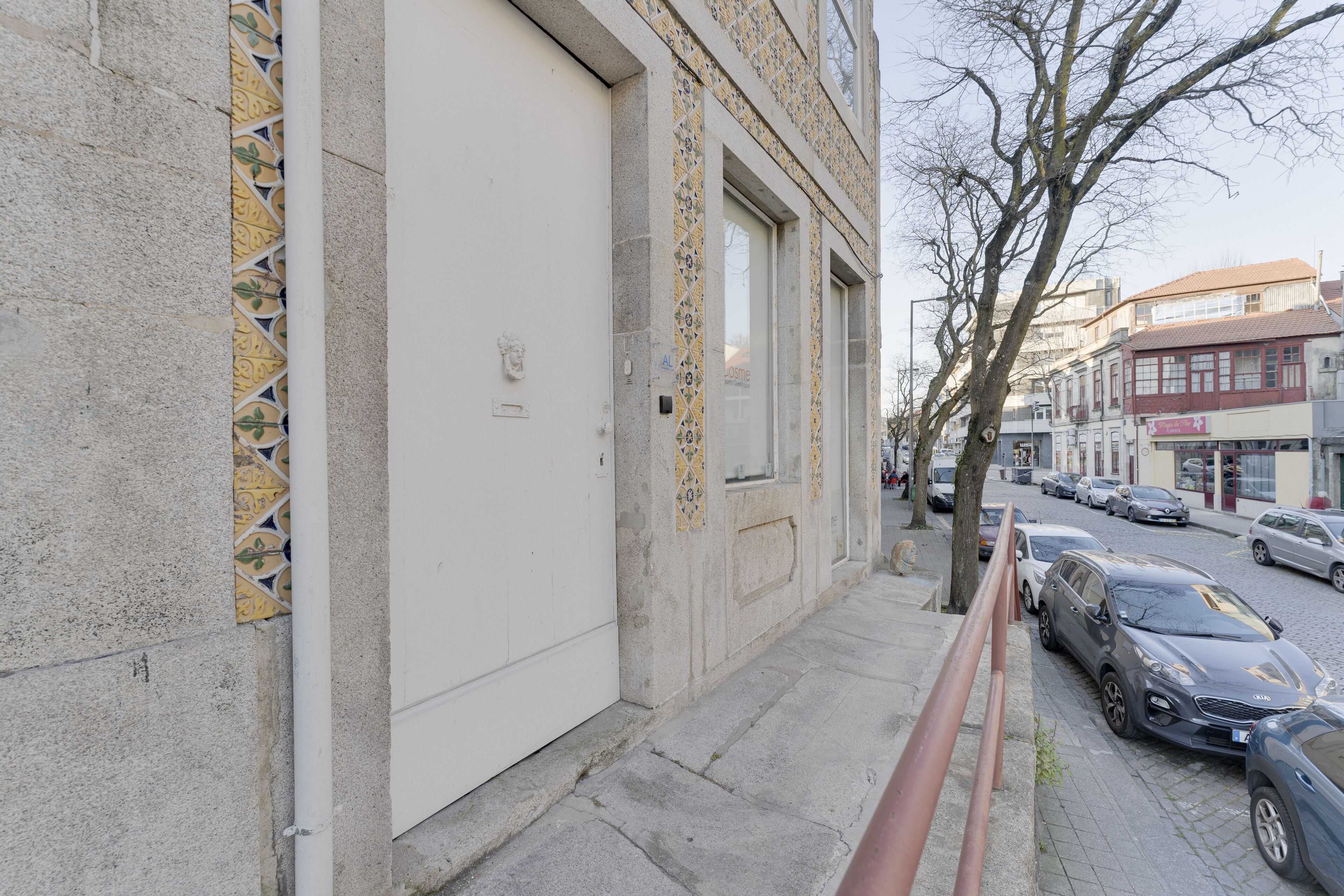 Straßenansicht eines Gebäudes mit einer großen weißen Tür und gemusterten Fliesen.