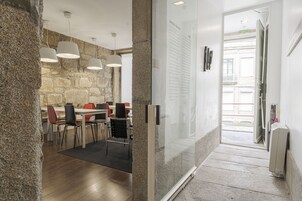 Un comedor moderno con una pared de piedra, una división de vidrio y vistas a la calle.