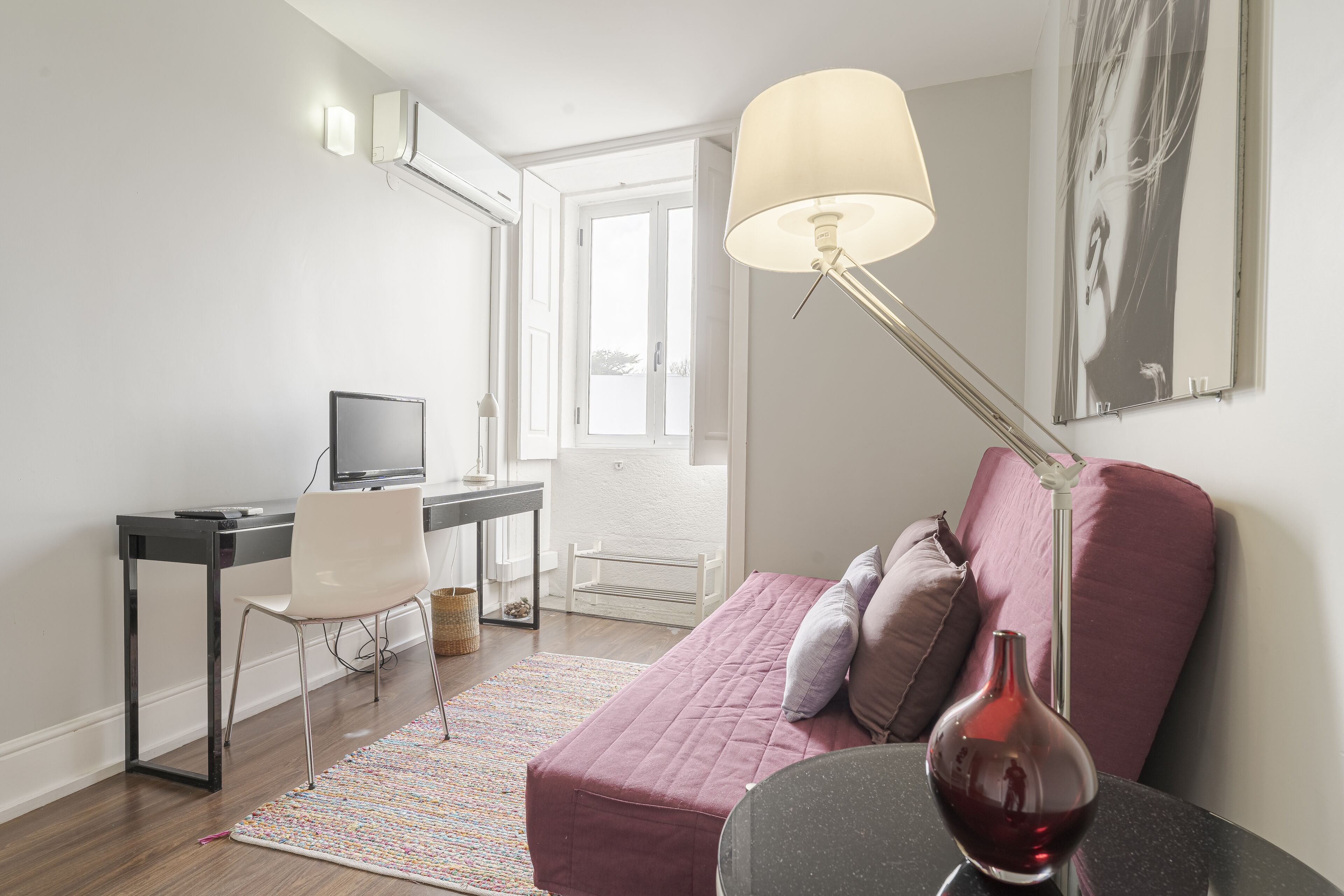Ein modernes Zimmer mit Schreibtisch, Stuhl und einer rosa Couch mit Kissen.