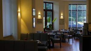 Un restaurante con cabinas y mesas, suelo de madera e iluminación instalada en las paredes.