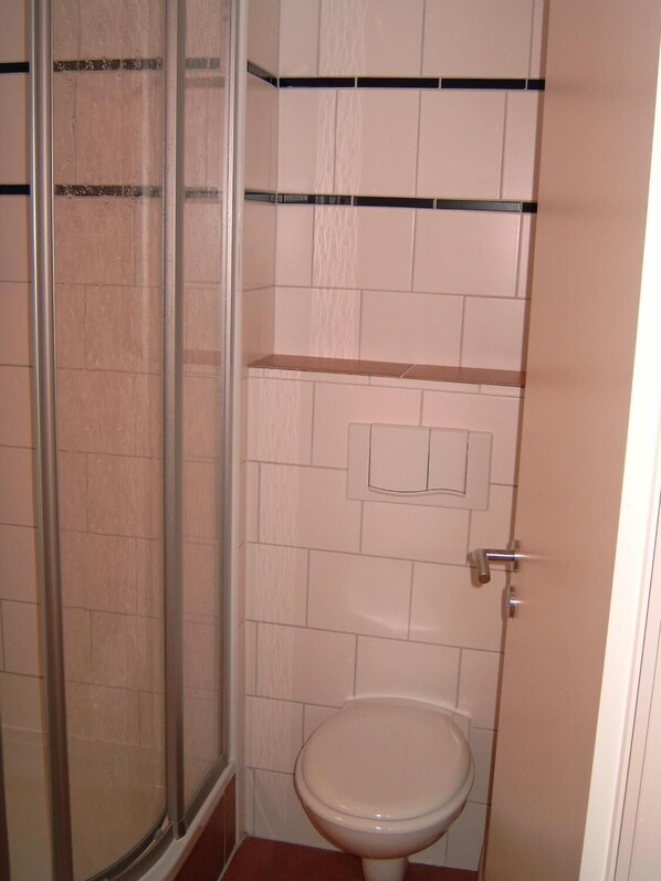 A bathroom with a toilet, a shower enclosure, and a sink. - Gästehaus Lisakowski (Görlitz)