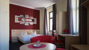 Una habitación de hotel con cama, escritorio, silla y una mesa redonda.