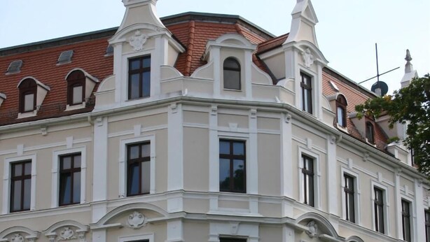 Un edificio de varios pisos con un estilo arquitectónico clásico, detalles ornamentales y una fachada simétrica.
