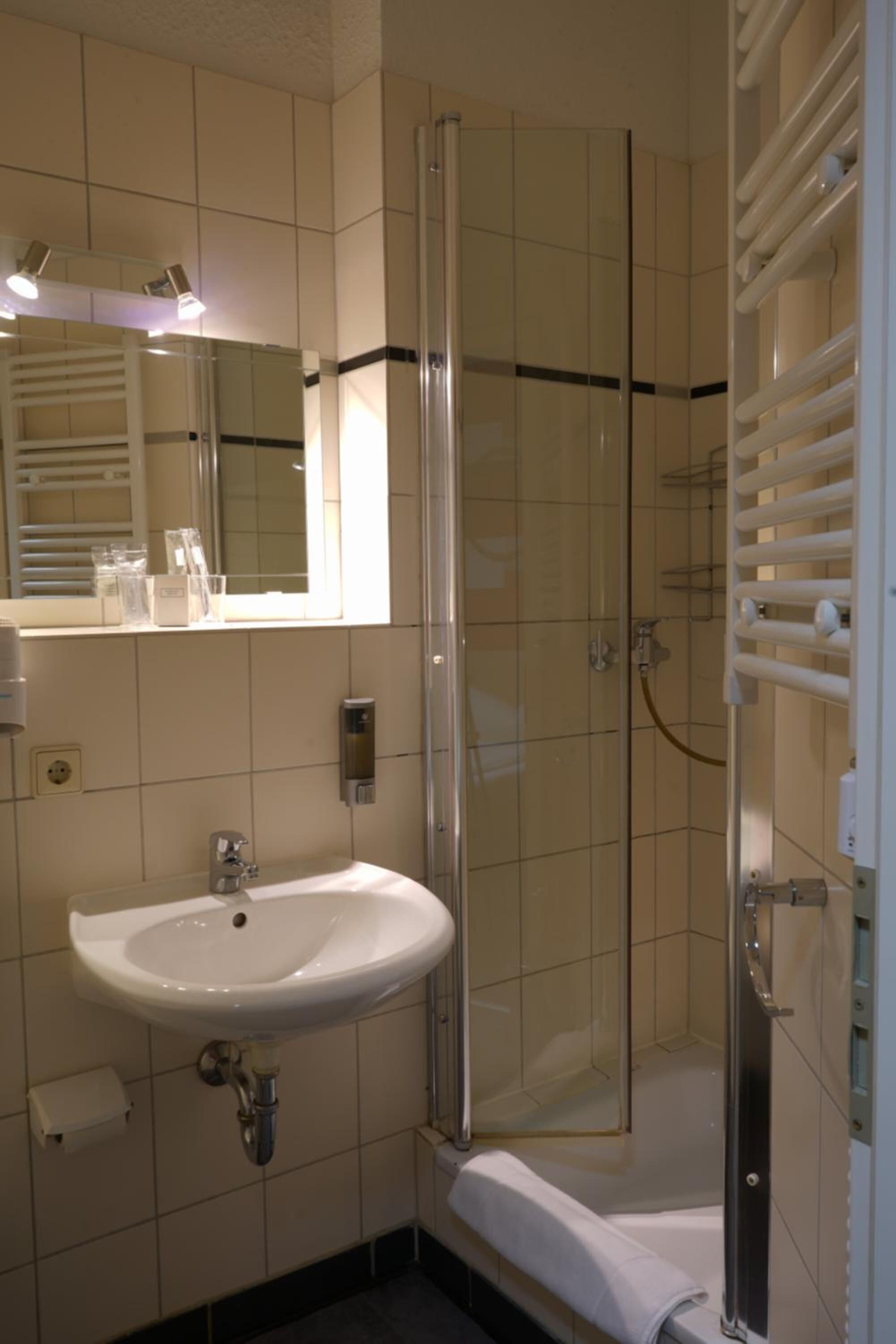 A bathroom with a white sink, a mirror, and a glass-enclosed shower.