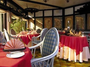 A restaurant interior with tables set for dining, chairs, and a view of the outside.