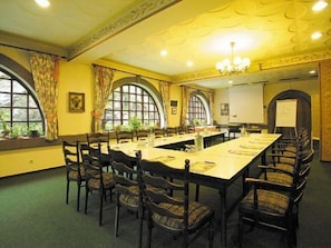 A conference room with a long table, chairs, and a projector screen.