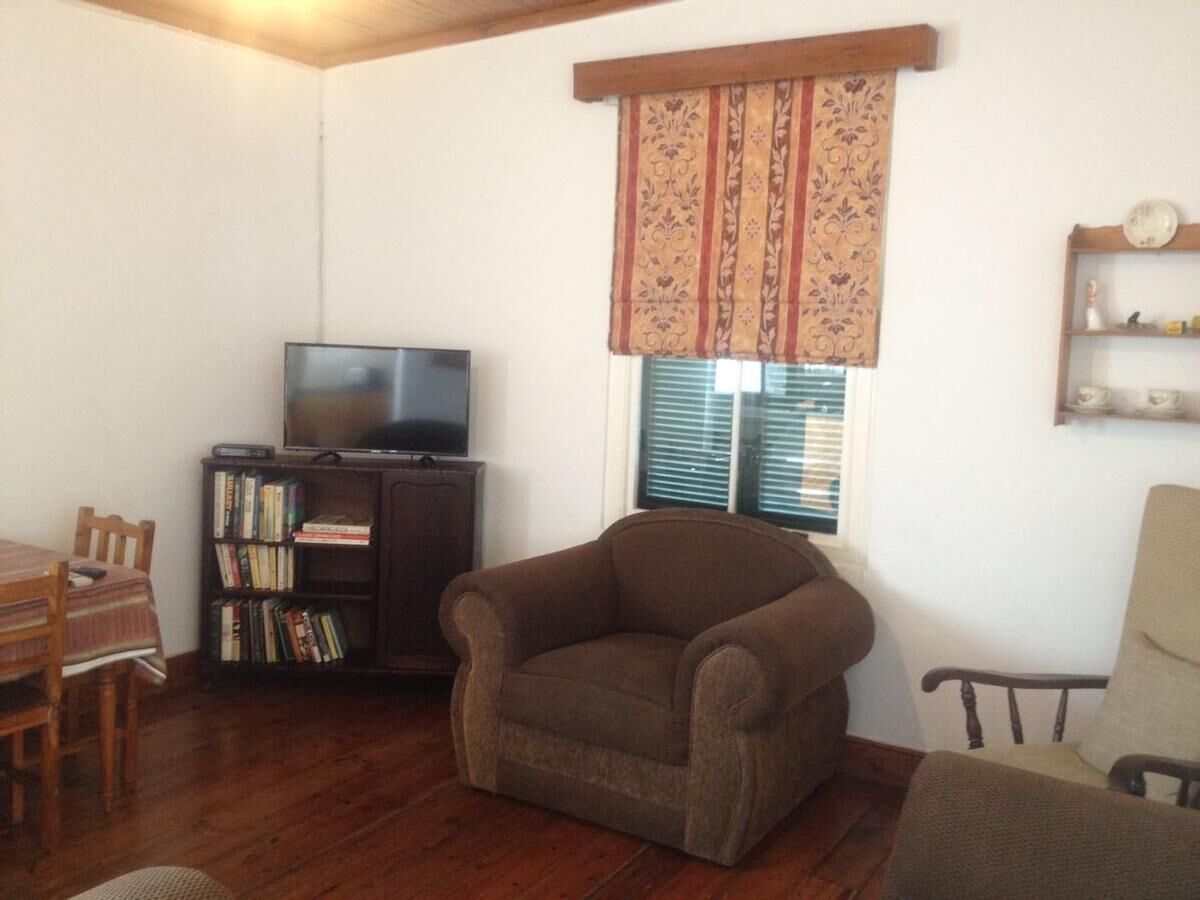 Una sala de estar con televisor, estantería y un sillón marrón.