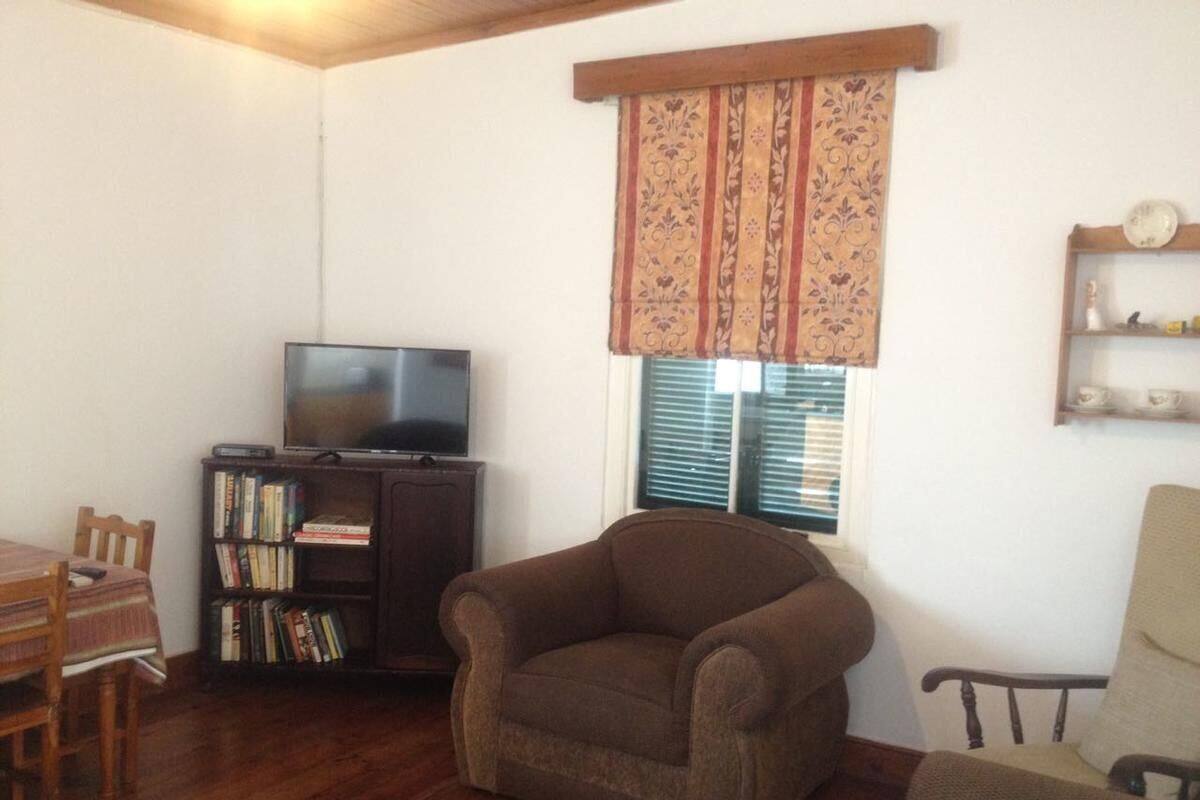 Una sala de estar con televisor, estantería y un sillón marrón.