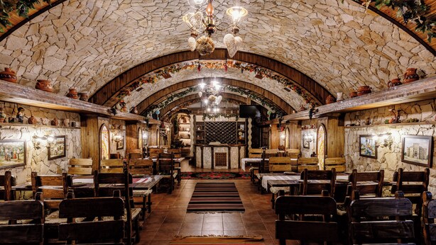 A restaurant with stone walls, wooden furniture, and a central altar. - President Hotel (Bacioi)