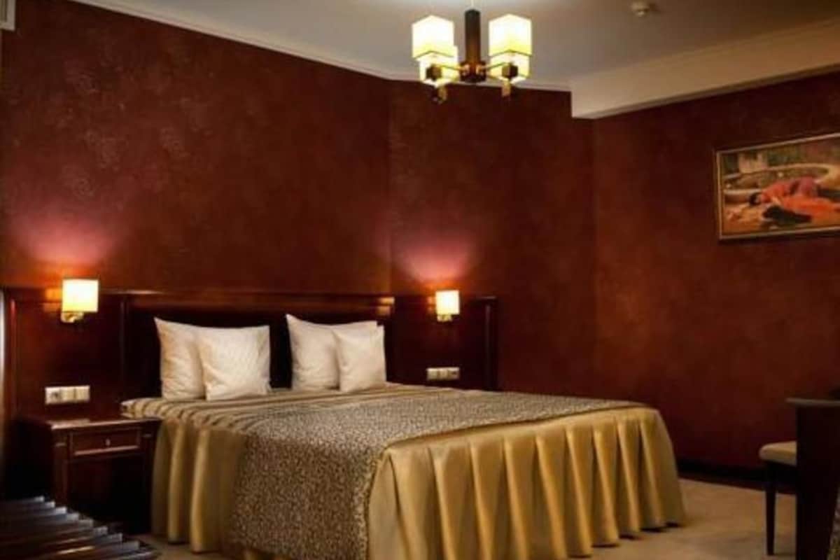Camera d'albergo con un letto grande, due comodini, un lampadario e un quadro appeso al muro.