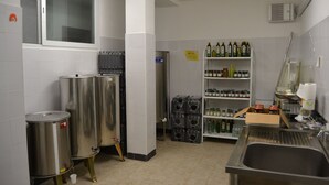 A kitchen with stainless steel appliances, a sink, and shelves stocked with bottles and jars. - Azienda Agrituristica Villa Arianna (Imperia)