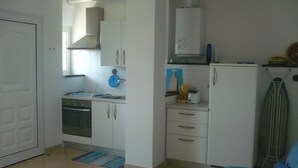 A compact kitchen with white cabinets, a stove, and a refrigerator. - Azienda Agrituristica Villa Arianna (Imperia)