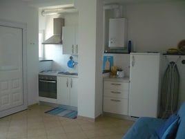 Una cocina pequeña con armarios blancos, estufa y refrigerador.