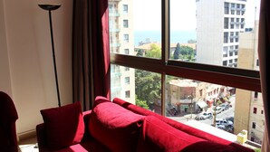 A room with a large window, red curtains, and a red sofa. - Bliss 3000 Furnished Studios (Beirut)
