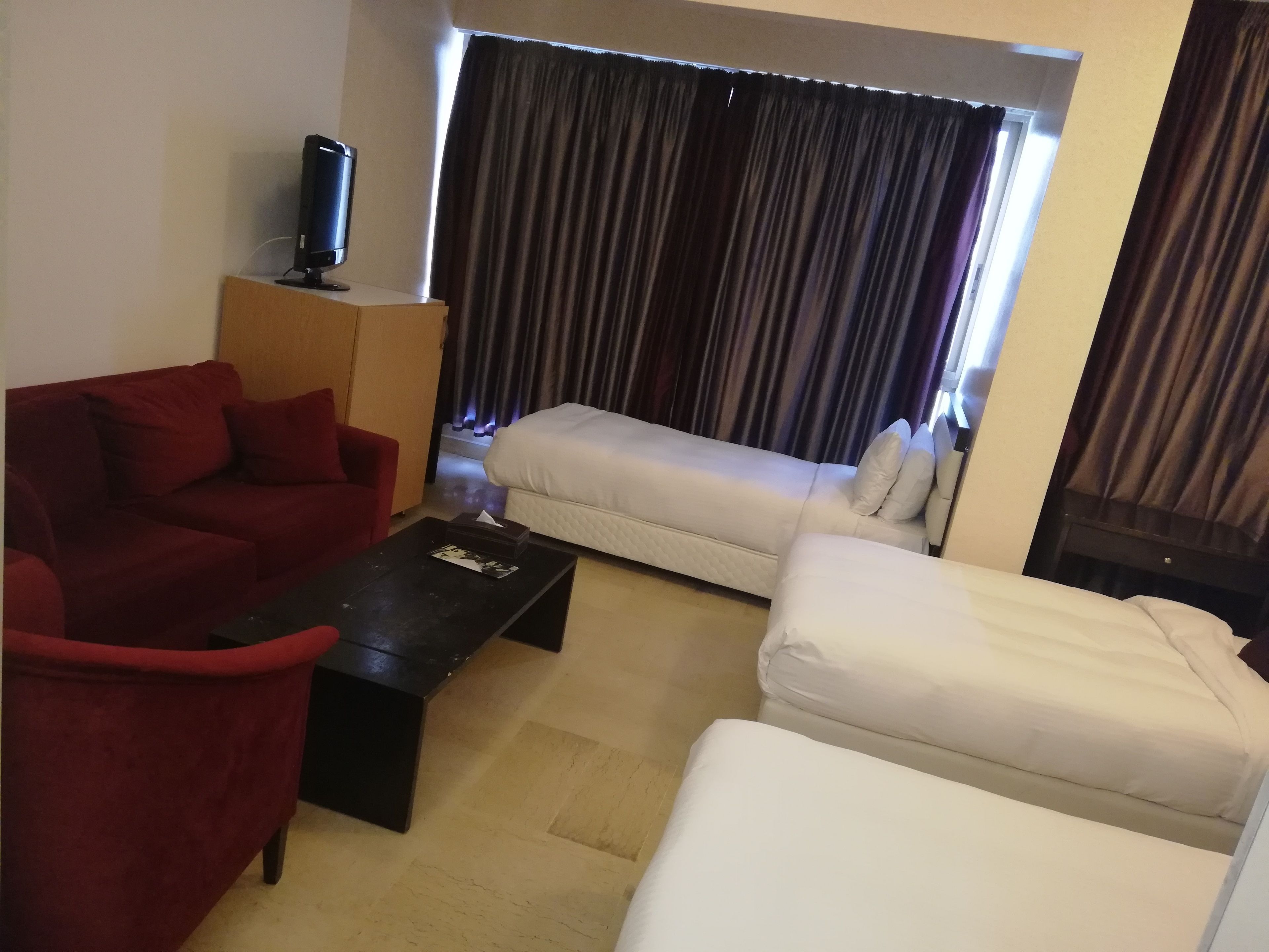 A living room with a red sofa, a white sofa, a black coffee table, and a television on a stand.