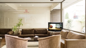 A modern waiting area with leather sofas, a flat-screen TV, and a 'No Smoking' sign. - Bliss 3000 Furnished Studios (Beirut)