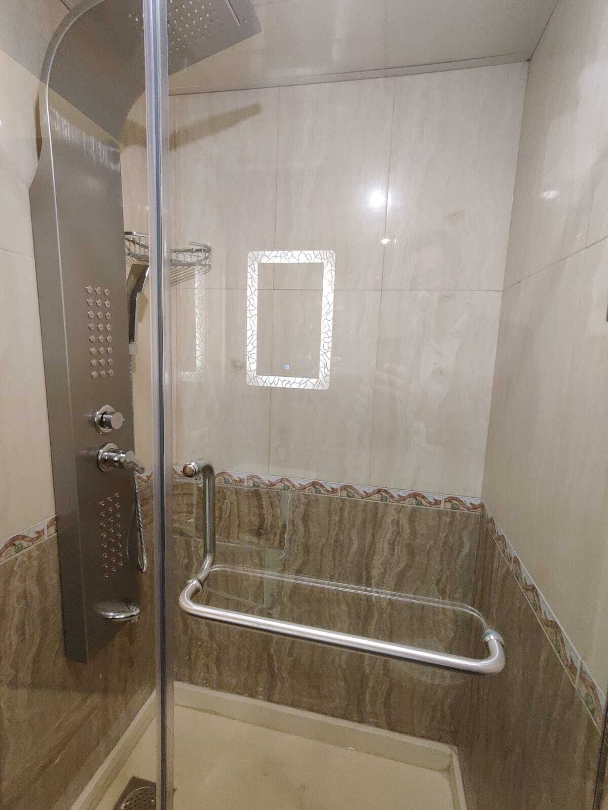 Eine Dusche mit Glastür, Bedienfeld und Haltegriff.