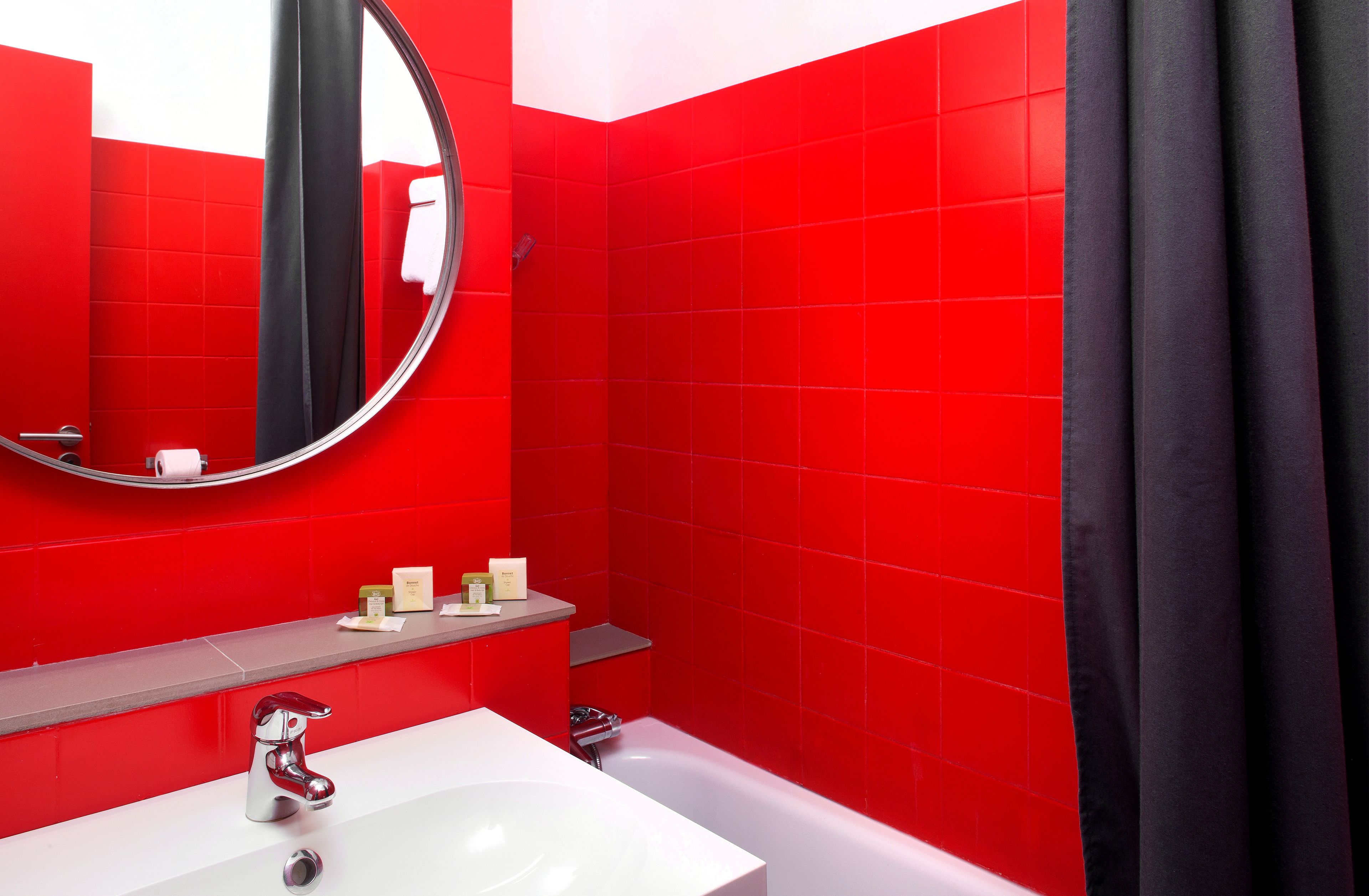 Un baño con baldosas rojas, un lavamanos blanco, un espejo y una cortina de ducha.