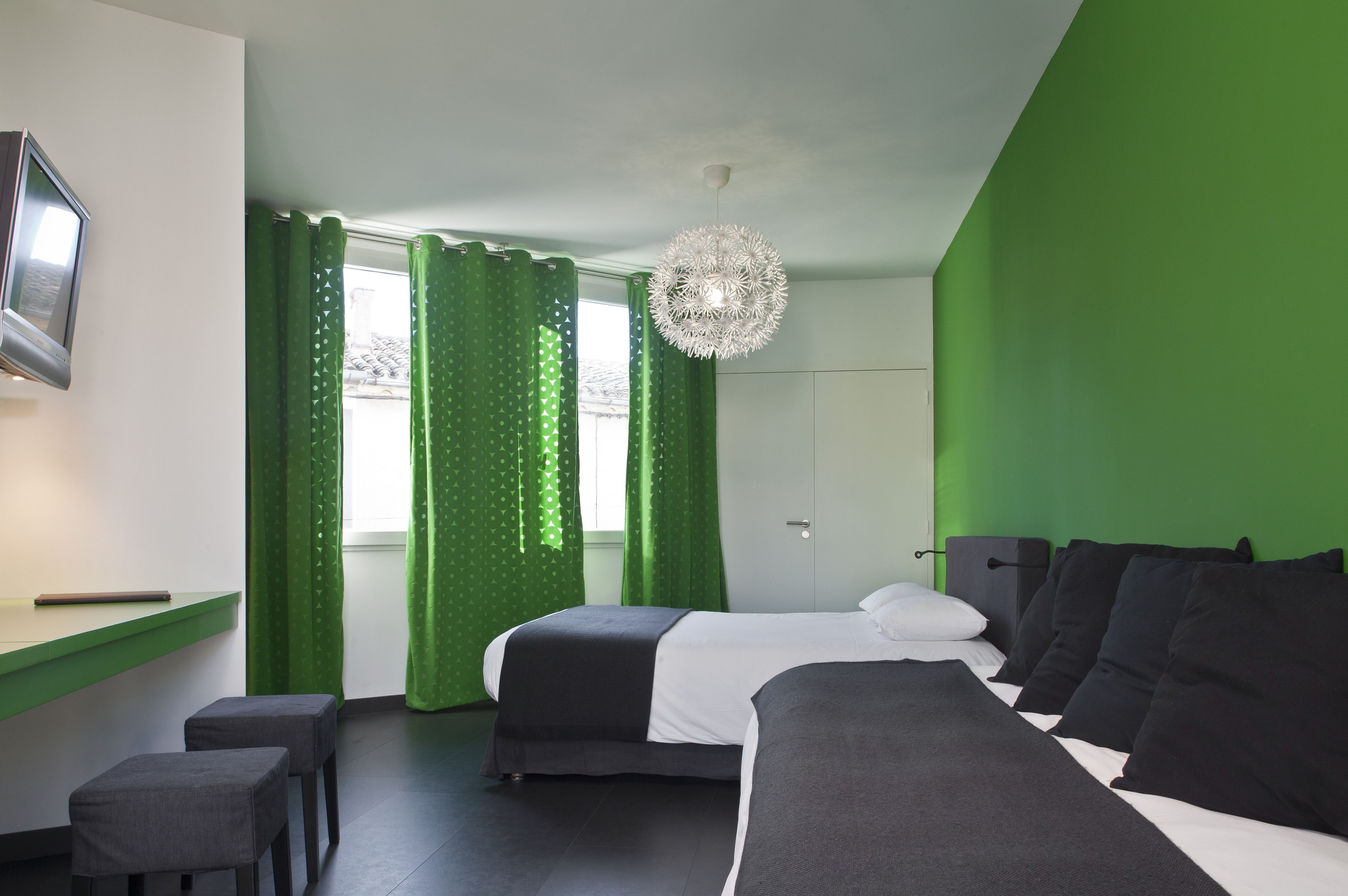A modern hotel room with a bed, a desk, and a chair.