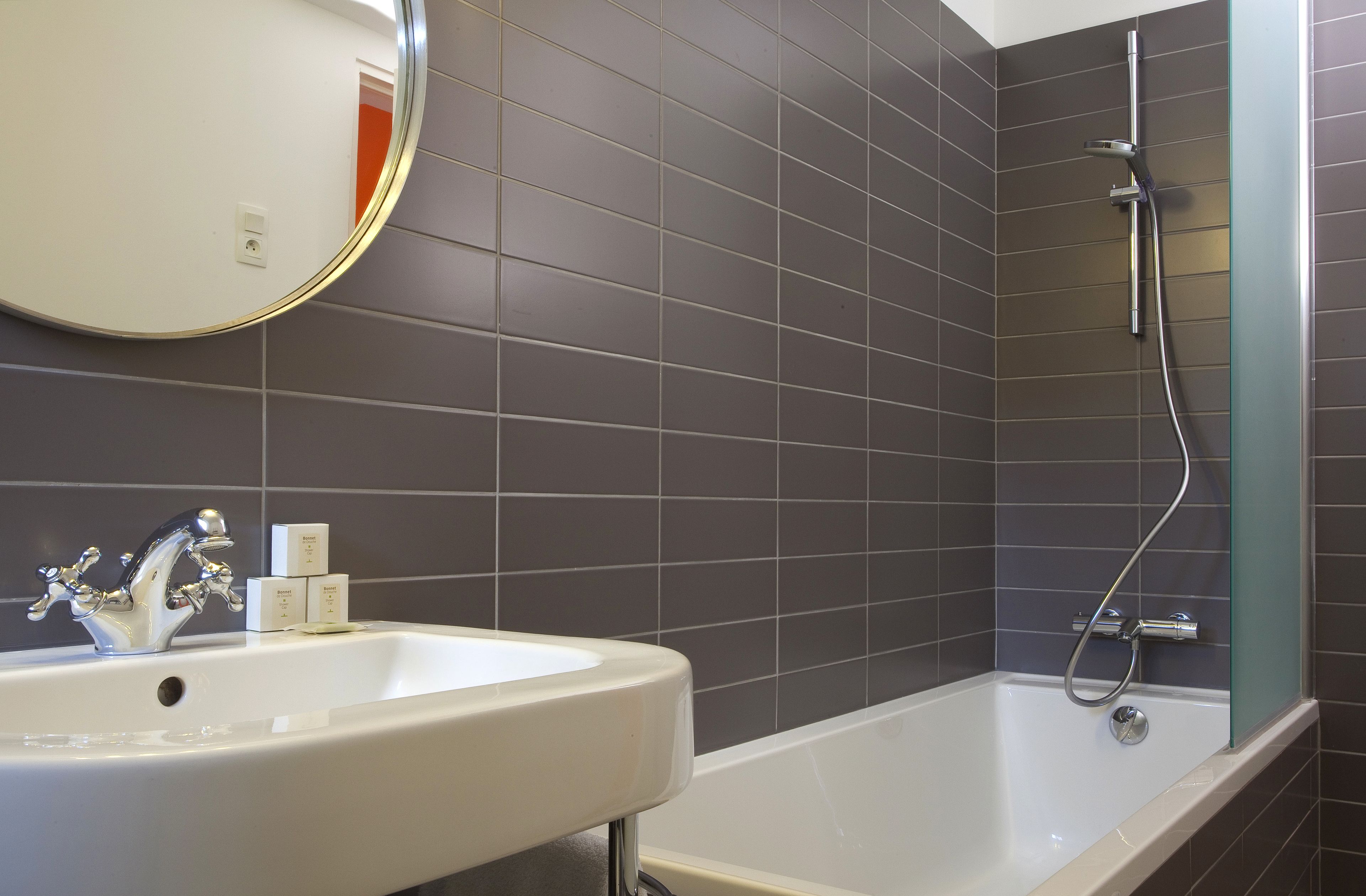 A bathroom with a white sink, a mirror, and a shower area.