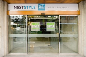 The entrance of Nest Style Hotel Santiago with clear signage and a modern glass facade.