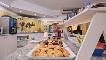 Zona de bufé con una variedad de pasteles y una máquina de café.