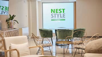 Un moderno vestíbulo de hotel con un cartel de Nest Style Hotel Santiago, asientos cómodos y una planta.