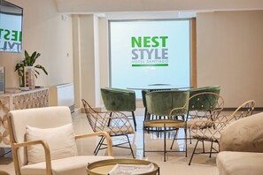 Un moderno vestíbulo de hotel con un cartel de Nest Style Hotel Santiago, asientos cómodos y una planta.