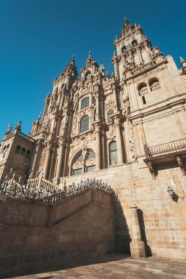 A grand historic building with intricate architectural details, including ornate columns and statues, and a prominent bell tower. - Nest Style Santiago (Santiago de Compostela)