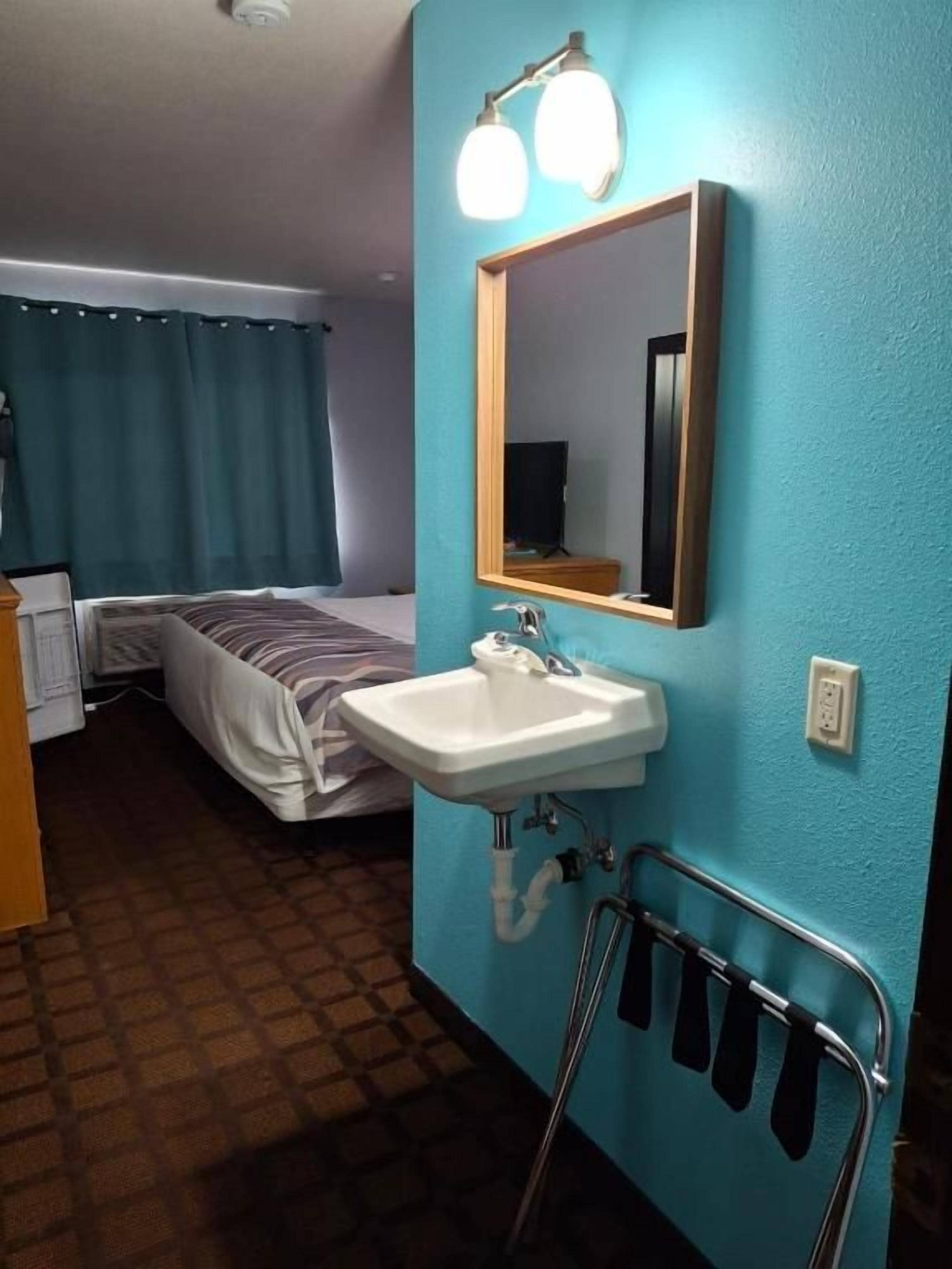 Habitació d'hotel amb llit, un lavabo i un mirall.