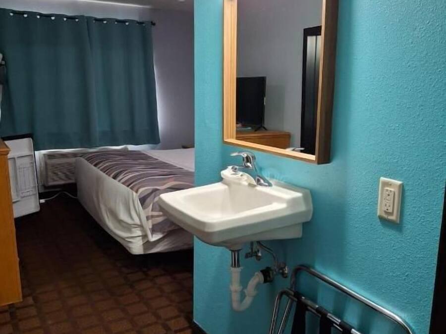 Habitació d'hotel amb llit, un lavabo i un mirall.