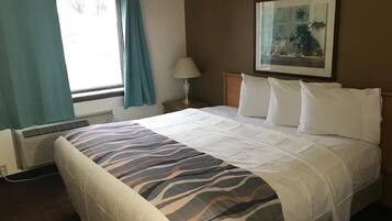 Una habitación de hotel con una cama, un ventanal con cortinas, una lámpara de pared y un cuadro enmarcado.