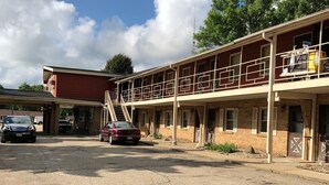 Un motel composé d’un bâtiment à deux étages, d’un espace de stationnement couvert et d’une allée en gravier.