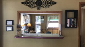 Un comptoir d’accueil avec un grand miroir, des certificats encadrés et une petite étagère avec des livres.