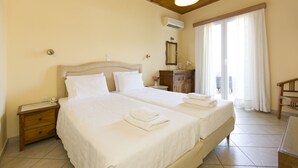 A hotel room with two beds, a wooden ceiling, a nightstand, a dresser, and a view of the outdoors through a window.