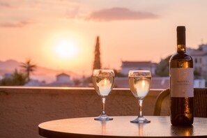 A sunset view with two wine glasses and a bottle on a table.