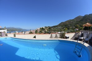 A swimming pool with a view of a hillside town and mountains in the background.