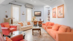 A living room with two sofas, a coffee table, and a TV. There are bookshelves and a lamp.