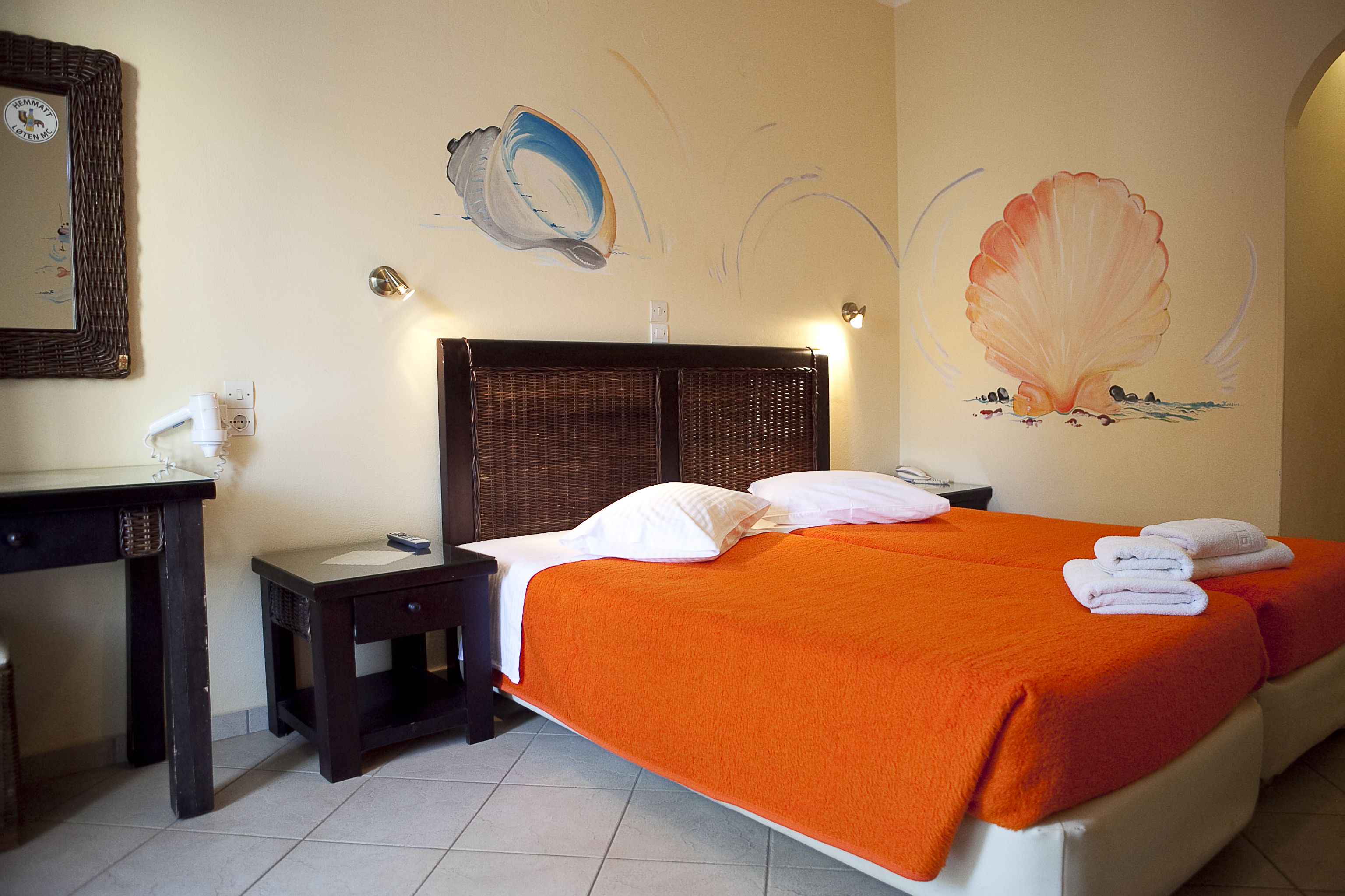 A hotel room with a bed, a nightstand, a desk, and a wall with a painting.