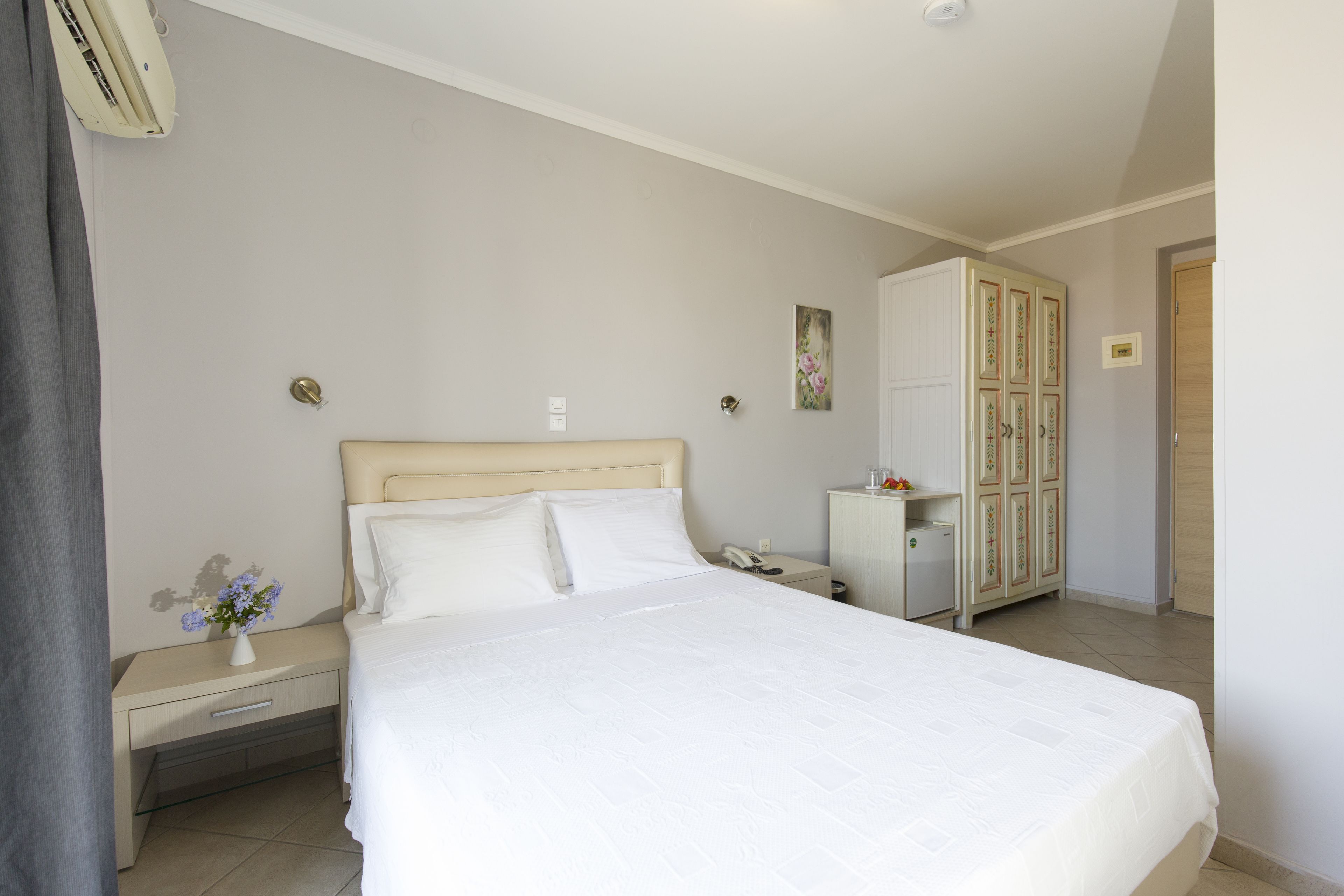 Une chambre bien rangée, avec un lit, une table de chevet, une commode, une armoire et un appareil de climatisation.