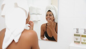 Une salle de bain avec un lavabo blanc, un miroir et deux flacons de lotion posés sur le comptoir.