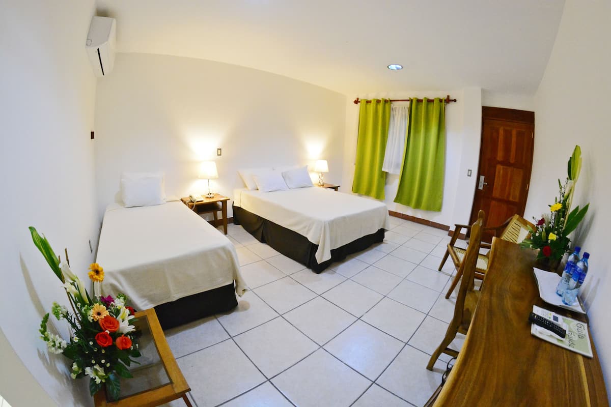 A hotel room with two beds, a dining table, and a small kitchen area.