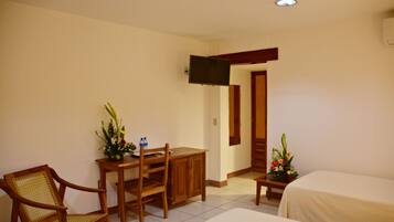 A hotel room with a wooden desk, a chair, a bed, and a television mounted on the wall.