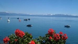 Un port de plaisance où sont amarrés plusieurs bateaux, un ciel bleu azur et une chaîne de montagnes à l’horizon.