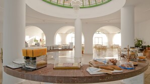 A spacious lobby with a central round table, a coffee station, and a glass ceiling. - Alexandra Beach Hotel (Kos)