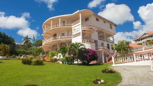 A multi-story hotel with a white exterior, balconies, and a well-maintained lawn. - Hotel Alexandrina (Ribishi)