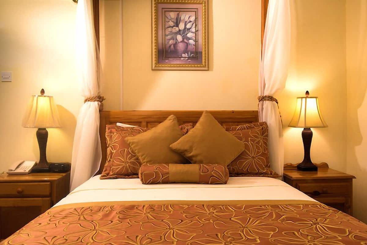 Ein Hotelzimmer mit einem Bett, zwei Nachttischlampen, einem Nachttisch mit Telefon und einem Gemälde an der Wand.