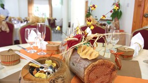 A dining table with a rustic centerpiece featuring a log and dried flowers. - Hotel Alexandrina (Ribishi)