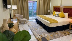 A hotel room with a bed, a desk, a chair, a TV, and a view of the outside. - Hotel Alexandrina (Ribishi)